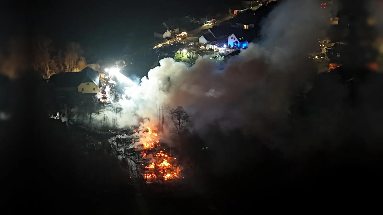 Einsatzkräfte von Feuerwehren sind beim Brand eines Sägewerks im Fichtelgebirge im Einsatz. Das Feuer löste einen Großeinsatz aus, insgesamt waren 235 Einsatzkräfte vor Ort. Das Feuer sei aus bislang unklaren Gründen in der Nacht ausgebrochen, sagte ein Polizeisprecher. (Bild: Stephan Fricke/dpa/NEWS5)