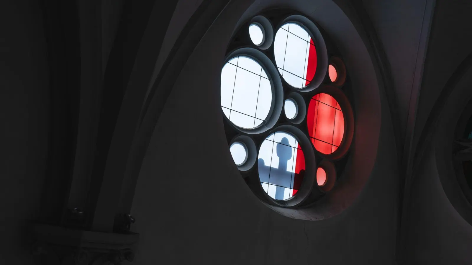 Licht wirft den Schatten eines Kreuzes durch ein Kirchenfenster. (Bild: Nicolas Armer/dpa/Symbolbild)