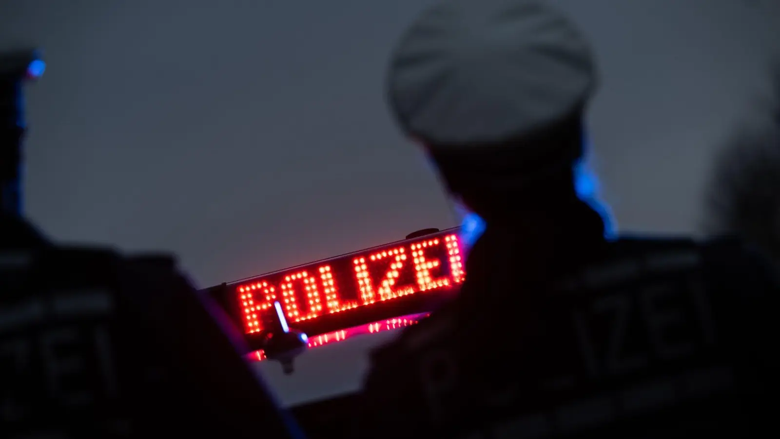 Zwei Polizisten stehen vor einem Polizeifahrzeug. (Bild: Marijan Murat/dpa/Symbolbild)