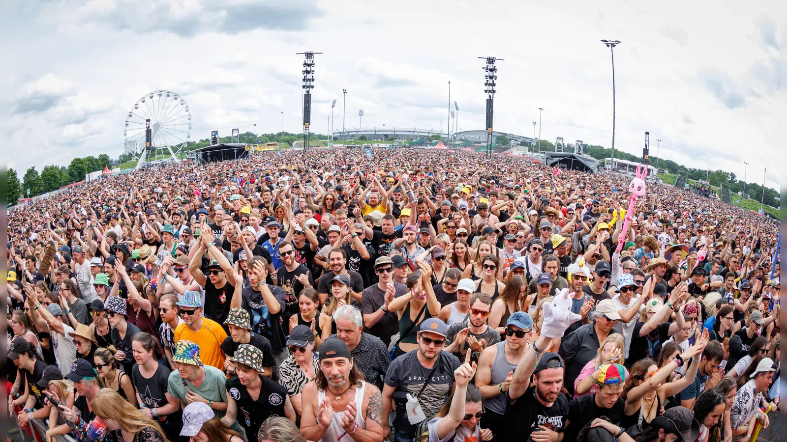 Das Publikum feiert auf Rock in Park. Im Hintergrund ist das Riesenrad zu sehen. Dort sollen Männer rassistische Parolen gerufen haben.  (Bild: Daniel Karmann/dpa)