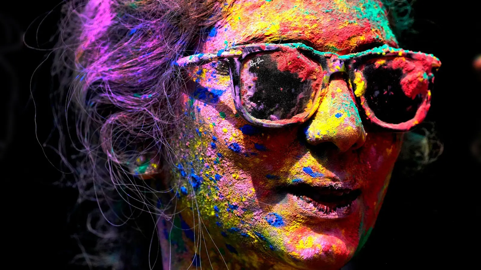 Das Gesicht einer Frau ist mit Farben bemalt.  (Symbolbild: Rajanish Kakade/AP)