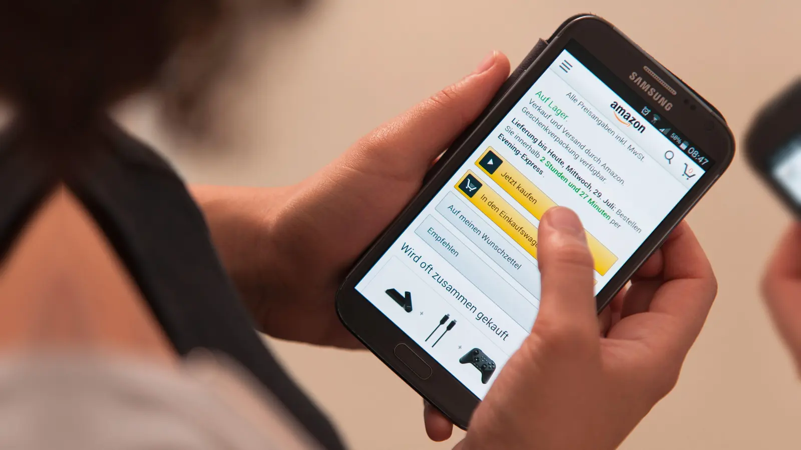 Eine Frau bedient die Smartphone-App des Onlinehändlers Amazon.  (Symbolbild: Sebastian Gollnow/dpa)