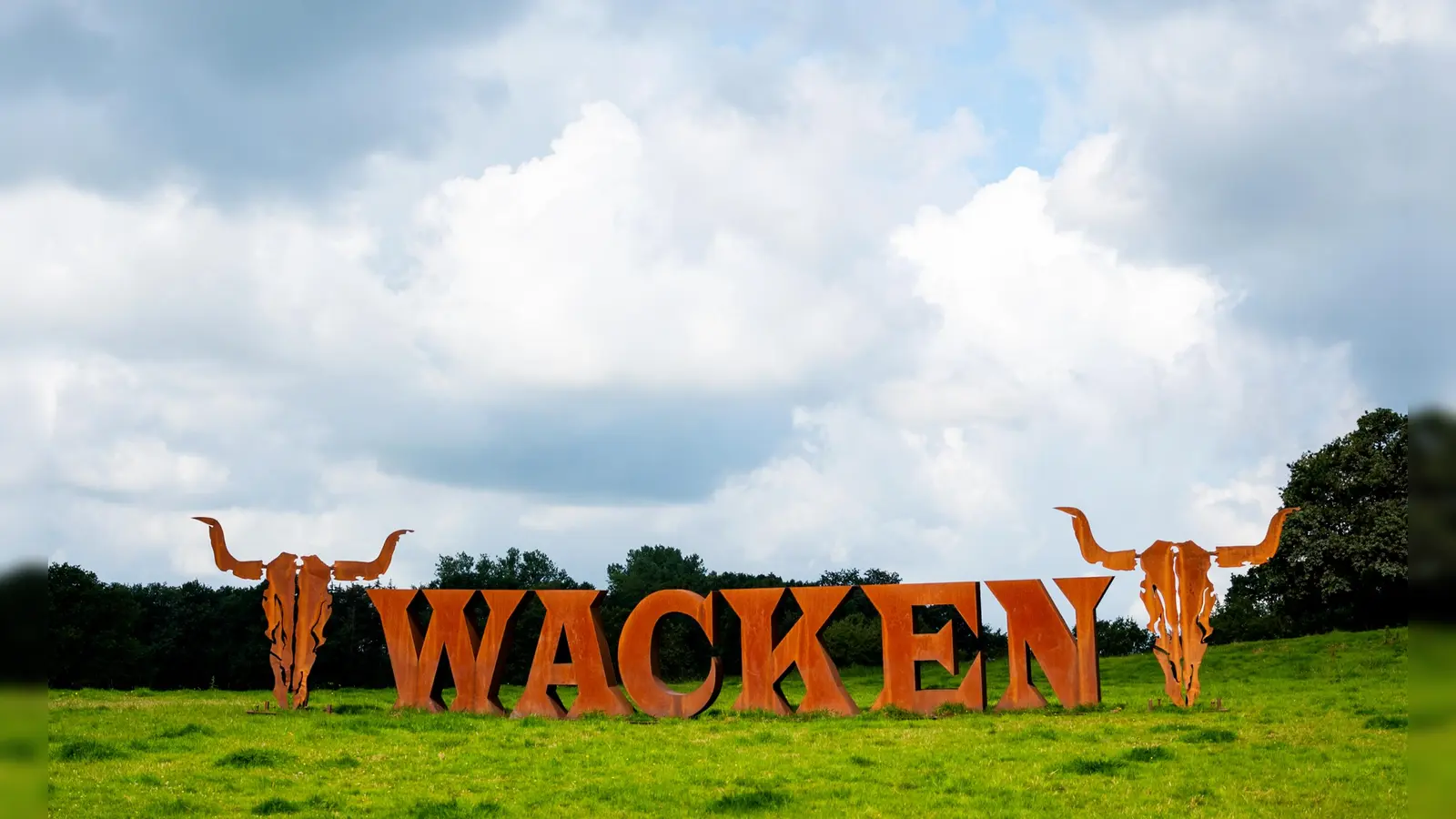 Der Schriftzug vom Heavy-Metal-Festival Wacken Open Air steht auf einer Wiese. In der Nacht auf Dienstag hat es auf dem Festival-Gelände gebrannt.  (Bild: Daniel Bockwoldt/dpa)