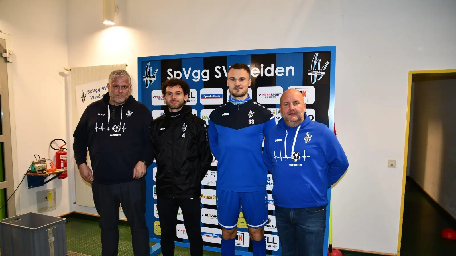 Erfolgsmeldung nach dem Sieg gegen Roding: SpVgg-SV-Vorsitzender Michael Kurz (rechts) und Sportdirektor Rüdiger Hügel (links) freuen sich, dass Igli Cami (Zweiter von links) und Maurico Göhlert länger am Wasserwerk bleiben. (Bild: Nachtigall/exb)