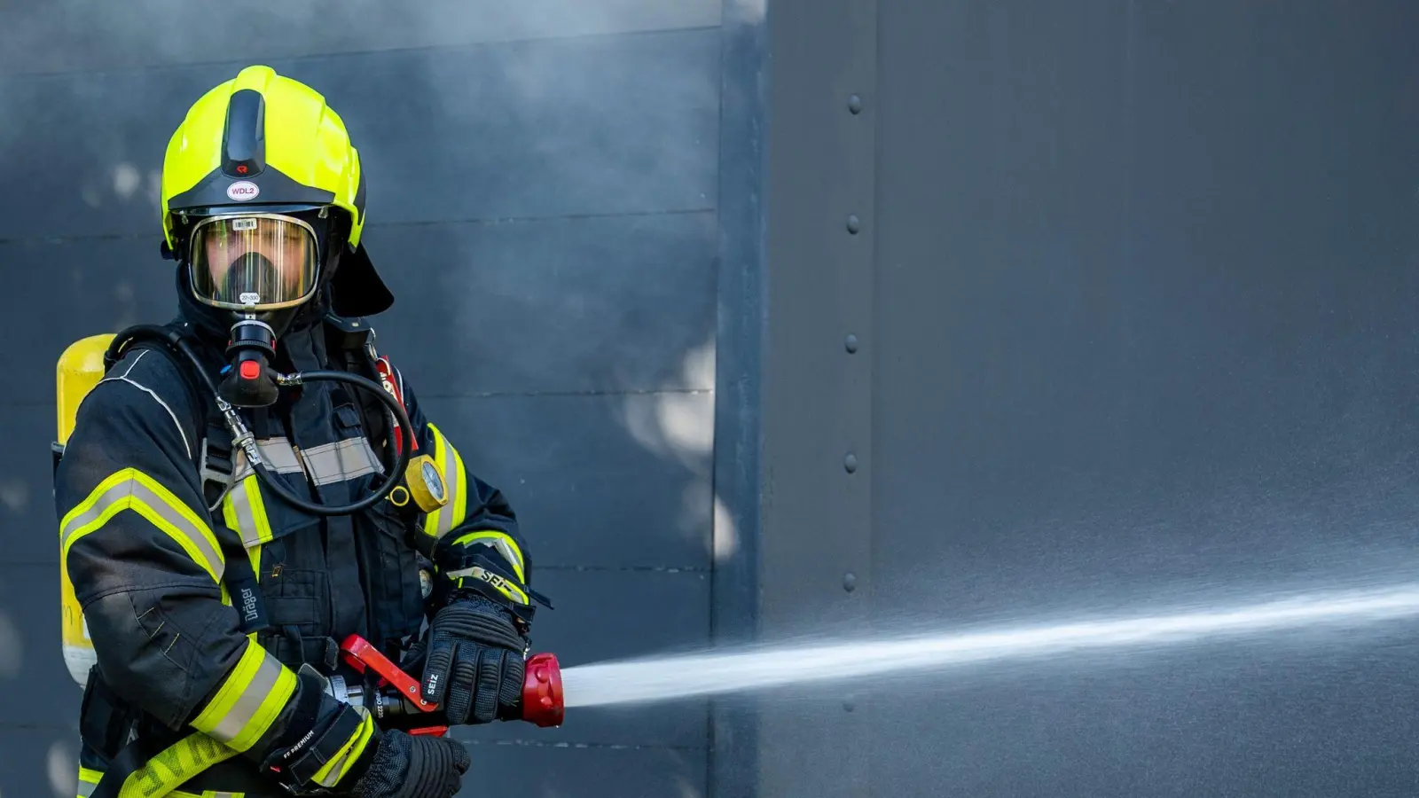 Mit Atemschutz löschte die Weidener Feuerwehr den Brand in einem grünen Container in der Müllumladestation.  (Symbolbild: David Inderlied/dpa)