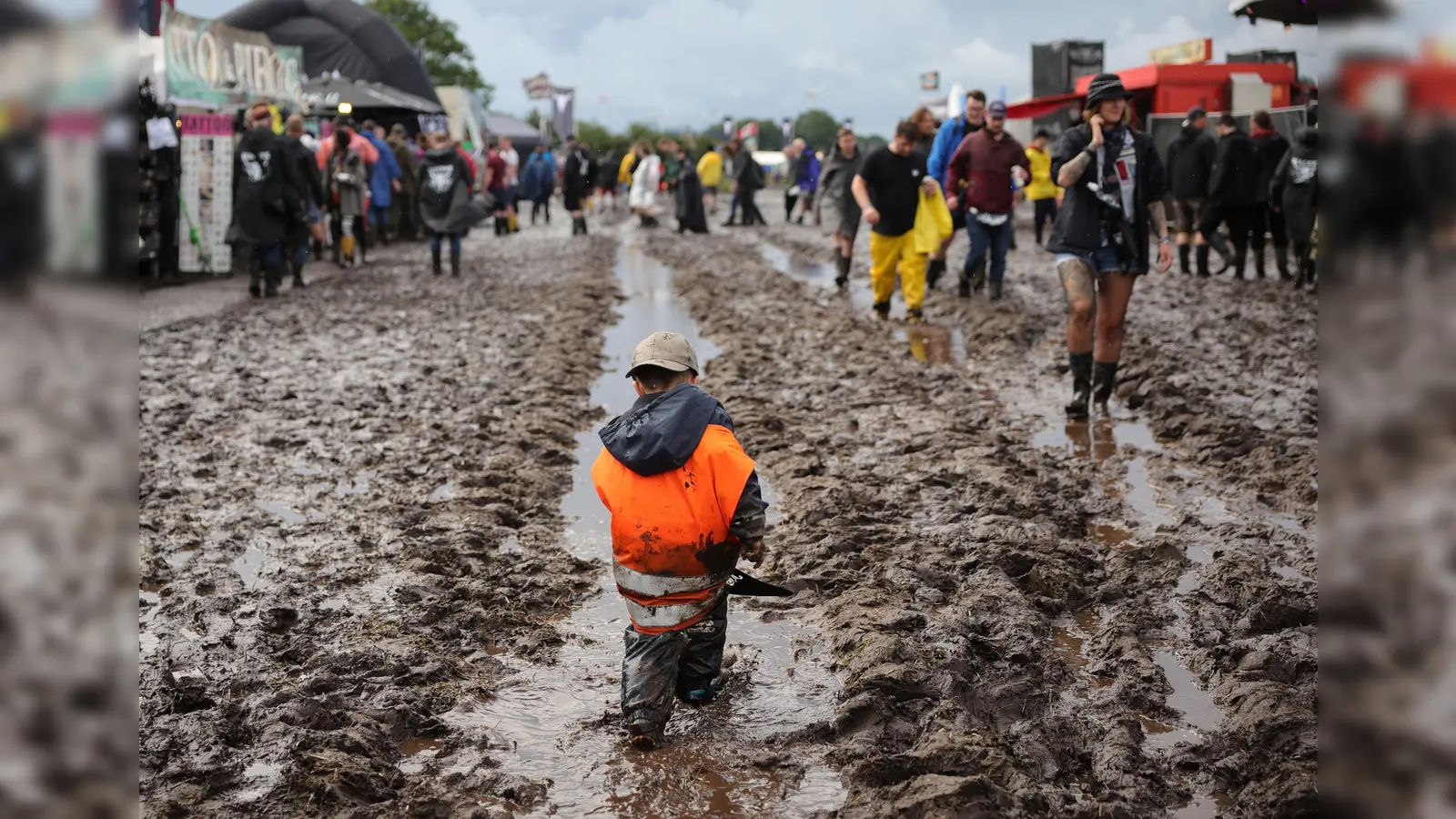 Metal-Fans sind auf dem schlammigen Festivalgelände unterwegs. Das Wacken Open-Air (WOA) vom 2. bis 5. August gilt als größtes Heavy-Metal-Festival der Welt und ist ausverkauft. (Bild: Christian Charisius)