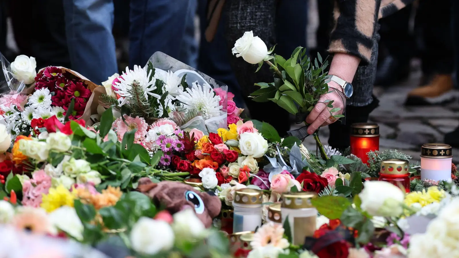 Menschen gedenken der Toten und Verletzten nach der Todesfahrt in Magdeburg. (Bild: Jan Woitas/dpa)