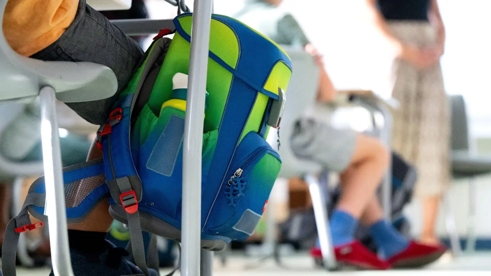 Ein Rucksack hängt im Klassenzimmer am Tisch eines Grundschülers. (Bild: Sven Hoppe/dpa/Symbolbild)